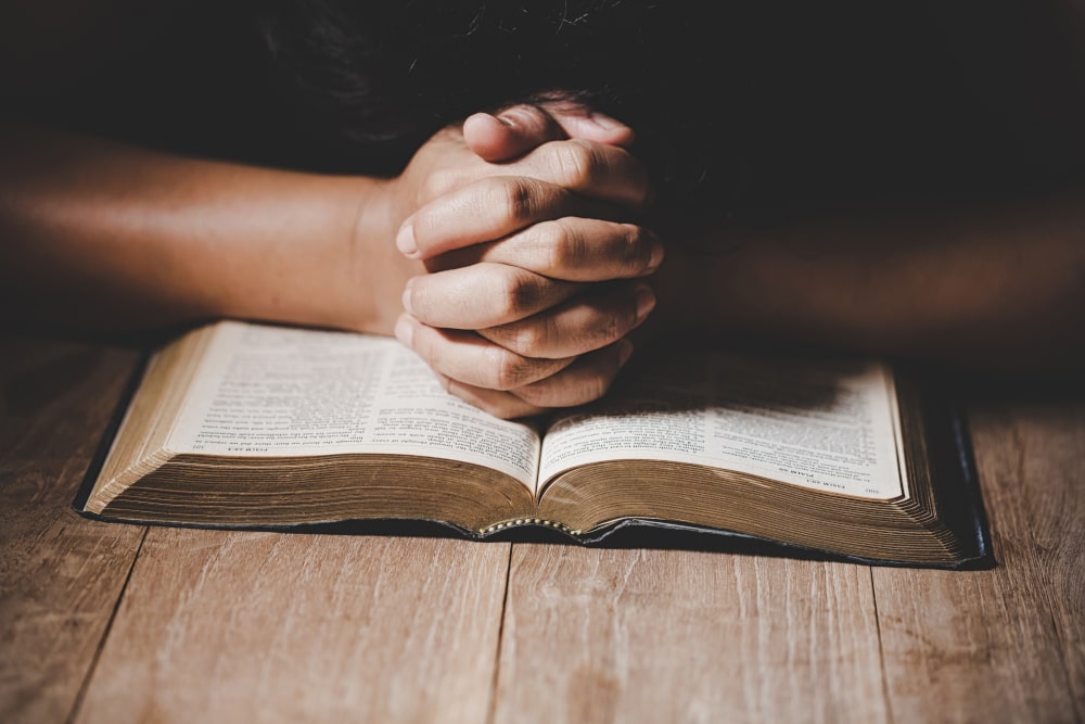 Hands clasped over open bible