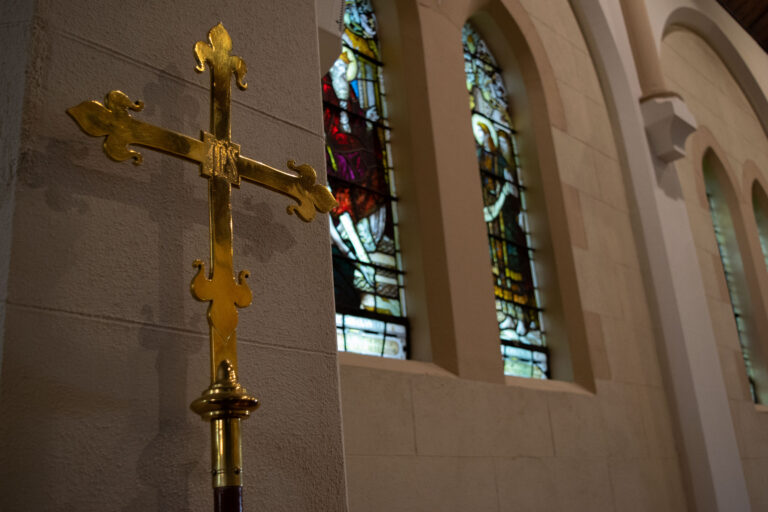 Gold cross with background stained glass windows