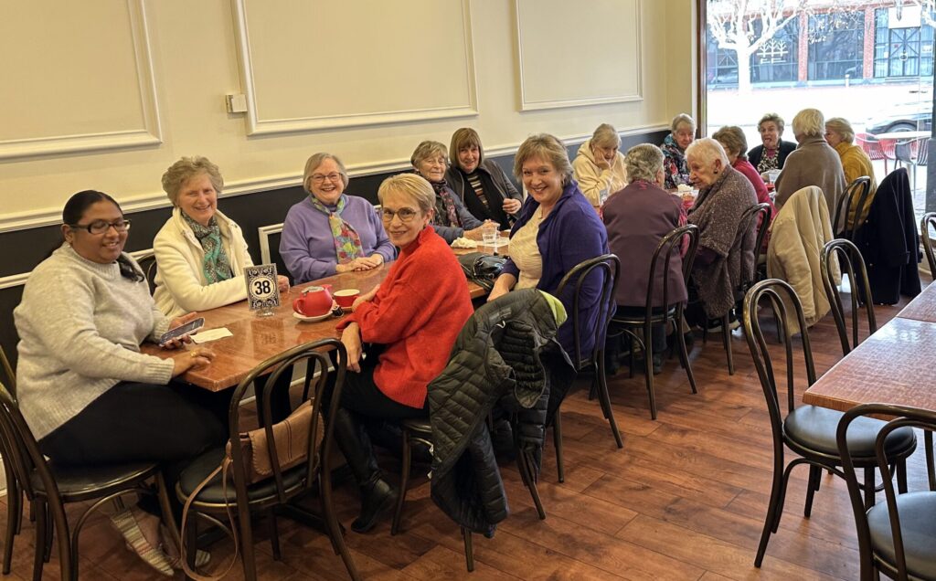 A large group of women gathered at a table for Women's Breakfast at Sfizio on the Parade
